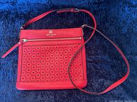 Full front view of red purse with floral cut-out design, strap extended