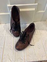 Pair of maroon colored low-top lace-up shoes, size 8.5, Ecco brand, shown from top down view on tiled floor.