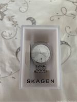 Front view of Skagen ladies stainless steel wristwatch in original transparent plastic Skagen box