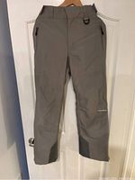 Front view of gray ladies ski pants showing zippered pockets, belt loops and D-ring on waistband.