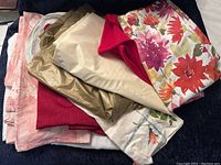 Top view of folded assorted tablecloths and placemats showing floral, solid, and pastel colors.
