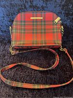 Front view of the red plaid purse with visible Steve Madden gold nameplate and zipper pull.