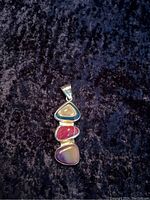 Front view of the sterling silver pendant showing the three cabochon gemstones vertically arranged on dark fabric background.