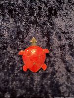 Front view of turtle-shaped brooch or pendant made with red coral and sterling silver.
