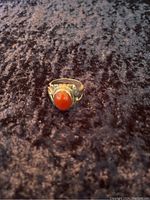 Front view of the silver ring showing the orange oval cabochon gemstone and detailed silverwork on the band.