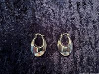 Front view of polished silver hoop earrings on dark fabric background
