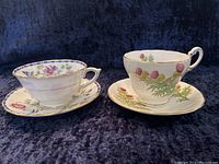 Two bone china cups and saucers placed side by side, showing front views highlighting floral and thistle designs.