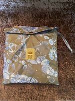 Closed storage pouch with flap and Rain Kiss label, olive green with blue bubble pattern