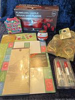 Photo showing the entire contents of the Xmas Gifts Lot including flameless candle, Dad jokes card, snowman stress ball, napkin rings, lipstick pens, stationery, and notepad.