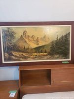 Full view of framed landscape painting showing mountainous scene, forest, and foreground pathway.