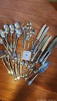 Full layout of all spoons, forks, knives and server on wooden surface