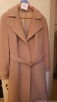 Full front view of tan knee-length coat on hanger