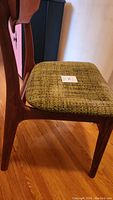 Side view of wooden dining chair frame with green upholstered seat