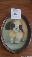 Full view of framed dog art showing oval wooden frame and print
