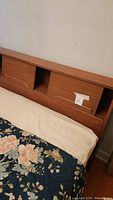 Close-up photo of headboard showing wooden finish, sliding panel doors, and cubby holes.