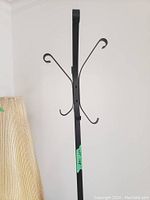 Full vertical view of the black metal coat rack showing the upper hooks and approximate height.