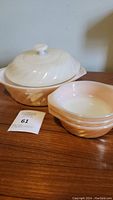 Photo showing cream peach lustre casserole dish with lid, and 3 small matching bowls stacked, all with swirl pattern texture and glossy finish.