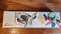 Box of the cutter showing the brand name Schnittfix with images of vegetables and a hand using the cutter.