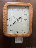 Front view of the rectangular wooden framed clock showing the dial and hands clearly.