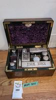Open vanity chest with purple interior showing various sterling silver vanity items including boxes, jars, bottles, and brushes