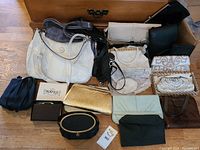 Overview photo showing all handbags and clutches laid out together on the floor in front of wooden furniture.