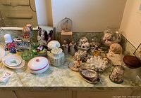 Wide shot of entire collection showing various glass, ceramic, and seashell decorative items on a countertop.