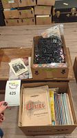 Open boxes showing various vintage sheet music and spiral bound music books on a wood surface with decorative music notes on top.