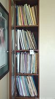 Three-shelf wooden unit filled with loose sheet music and instructional books