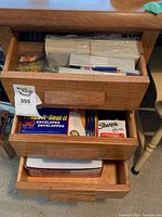 Opened drawers showing various office supplies including envelopes, notebooks, Sharpie markers, calculators, brass fasteners, push pins, tape, stapler, and staples.