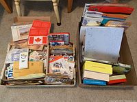 Box containing assorted postage stamps, envelopes, gift cards, sheet protectors, notebooks, and stationery items.