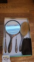 Overview of mirror, brush, two nail tools and small pouch in presentation box