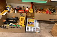 Overall view of the lot showing boxes containing toys and chemistry set with various toy parts and wooden figures.