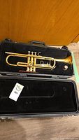 Brass trumpet in black padded molded hard case with lid open for display.