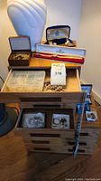 Lot overview showing two wooden storage chests stacked with drawers, plastic jewelry organizer tray, Tissot watch box, and Gruen jewelry box