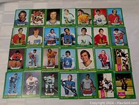 Front view of 35 assorted 1973-74 O-Pee-Chee hockey cards laid out in rows, showing player images and green borders.