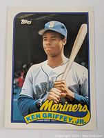 Front side of 1989 Topps Ken Griffey Jr rookie baseball card showing player's image in Mariners uniform holding bat with yellow text and Topps logo.