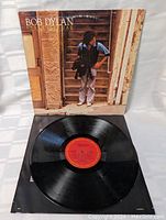 Vinyl LP record and its cover showing the red label of the record and the photo of Bob Dylan on the cover.