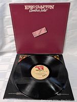 Front view of the vinyl record "Another Ticket" by Eric Clapton with the record partially out of the sleeve, showing the label.