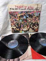 Photo of two vinyl records and album cover featuring colorful artwork and handwritten title, showing condition and contents of the lot.