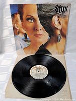 Photo showing the vinyl record partially out of the album cover, clear view of record label and cover artwork.