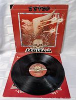 Open view showing vinyl record and inside of front cover with artwork and label on record.