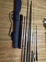 Overview of two rod cases and seven fishing rods laid out showing condition and variety