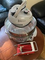 White Big Boss air fryer on glass bowl with metal rack inside on wooden table.