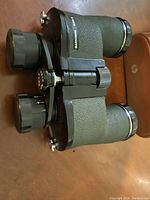 Top and side view showing textured green body, adjustment knobs and eyepieces.