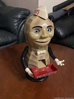 Front view of the vintage Mr. Peanut dispenser showing its detailed face, hat labeled 'PEANUTS', smiling mouth, blue eyes, and red peanut tray with 'PEANUTS' printed.