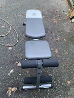 Exercise bench viewed from above showing padded backrest and seat with foam roller leg support.