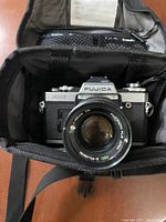 Fujica AX-5 camera with attached 55mm lens inside padded compartment of bag.