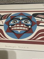 Close-up of Native American inspired art print featuring geometric face and shapes in red, blue, black, and white.