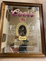 Coors mirror beer sign with wood frame, gold, purple, white, and black lettering and decoration, measuring approximately 20x16 inches.