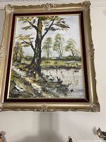 Full view of framed original oil painting showing a landscape scene with a pond, large prominent tree in foreground, ducks in water, and trees in background.